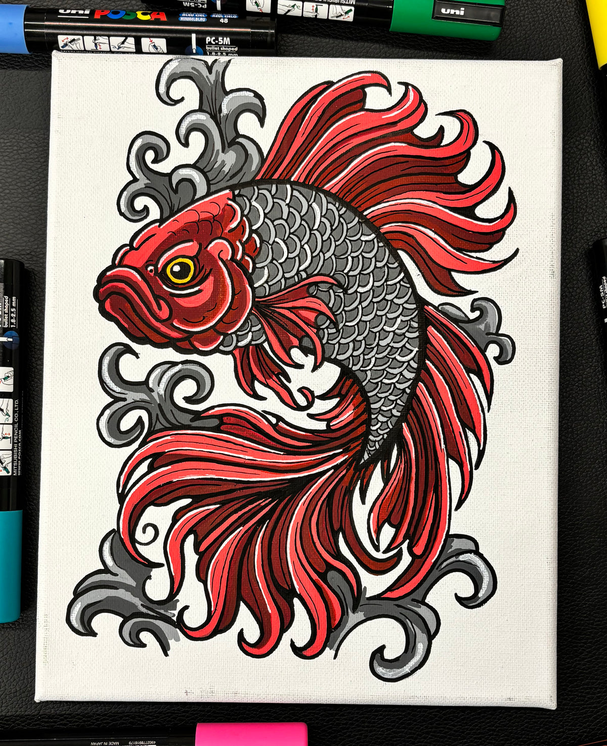 Colorful red beta fish design on a white background with markers visible below.